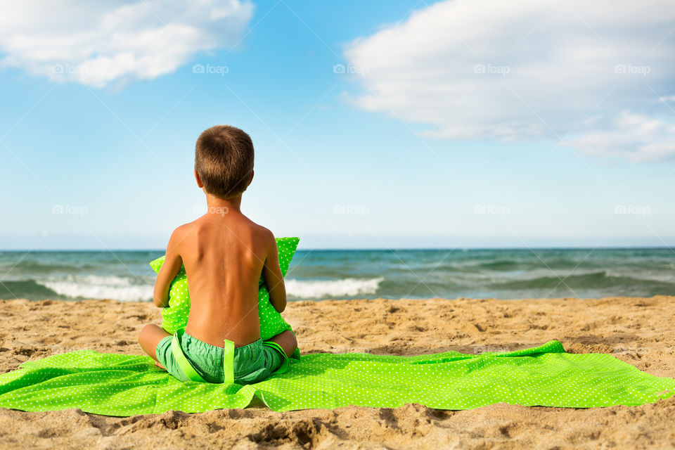 Rear view of boy sitting on beach