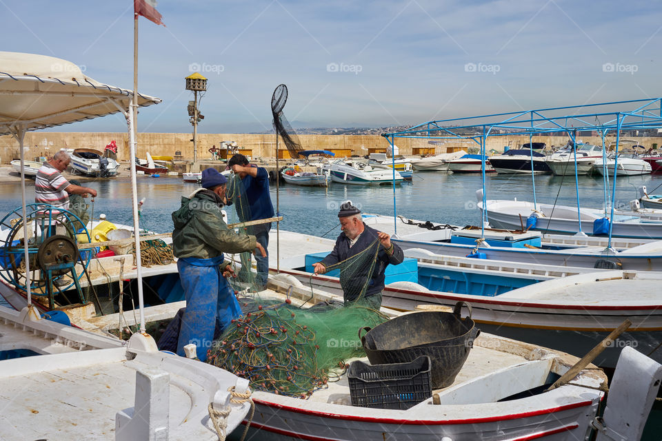 The fishermen repairing the nets on a fishing boat in the port. 