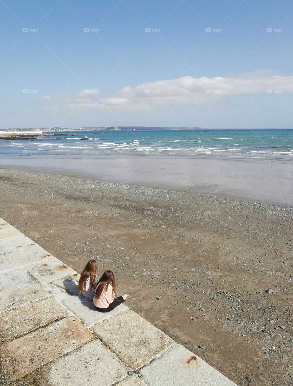 Sunny spring day in England. Two girls on the beach. Sea, sand, sun.