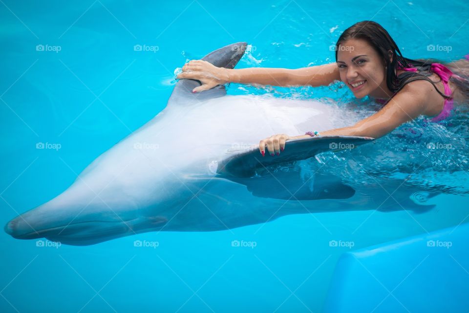 Woman swimming with dolphin in pool