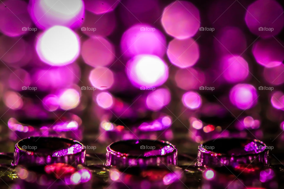 A macro shot of some gemstone net mesh. Three gems are in focus in the foreground with light reflected in front & behind the gems creating circles of reflected magenta light rising in the background. 💎