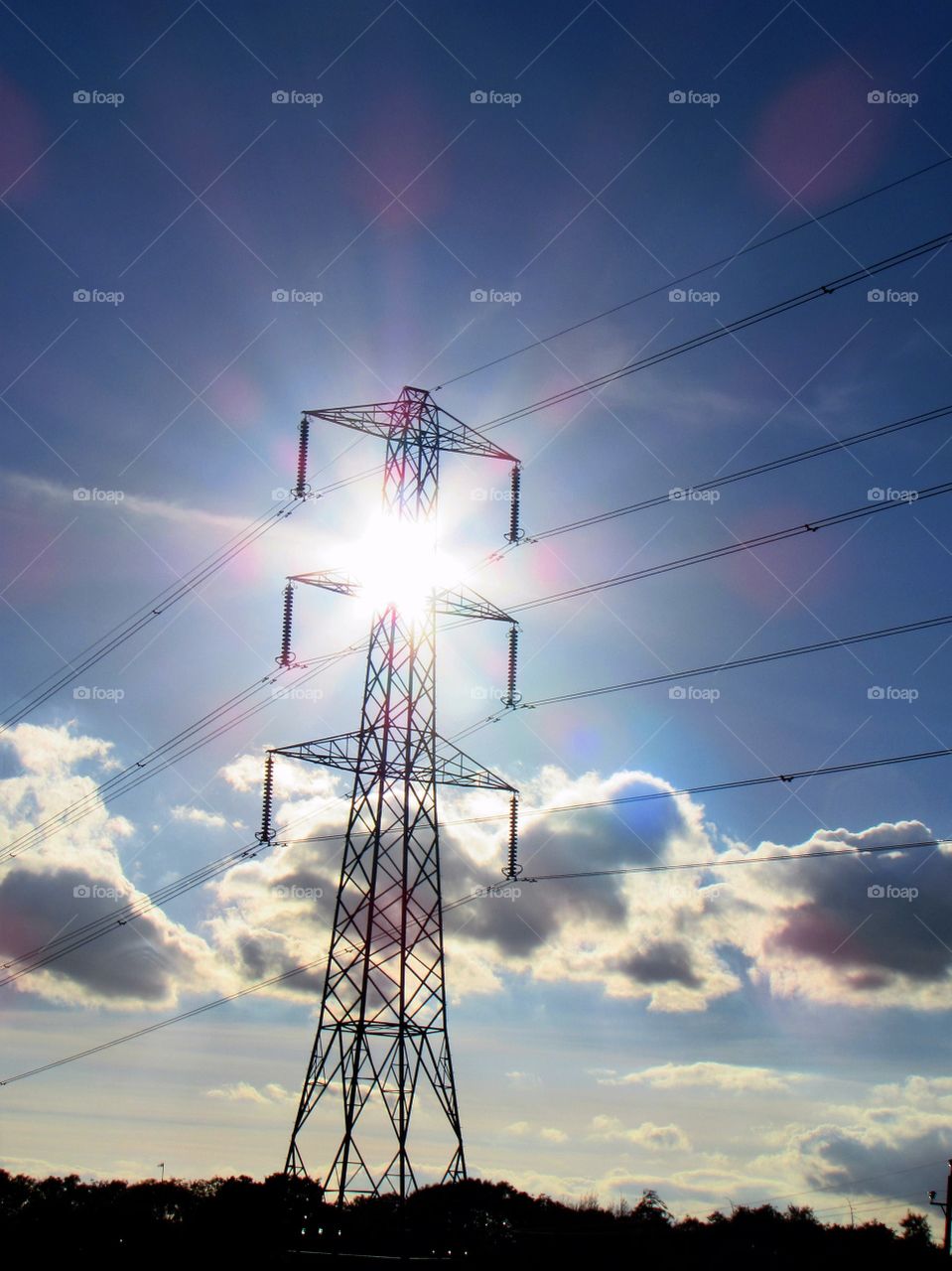 The Sun's rays appear to emit from the electricity pylon