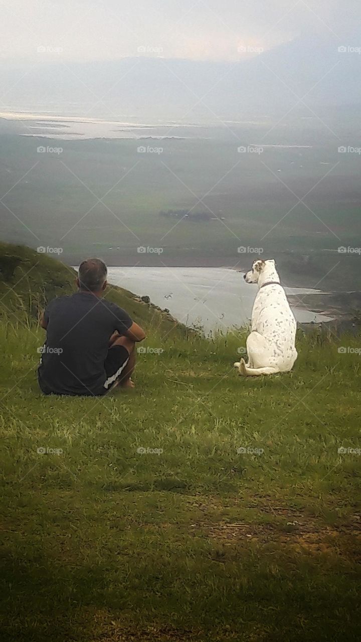 just a man and his dog taking in the view during a walk.