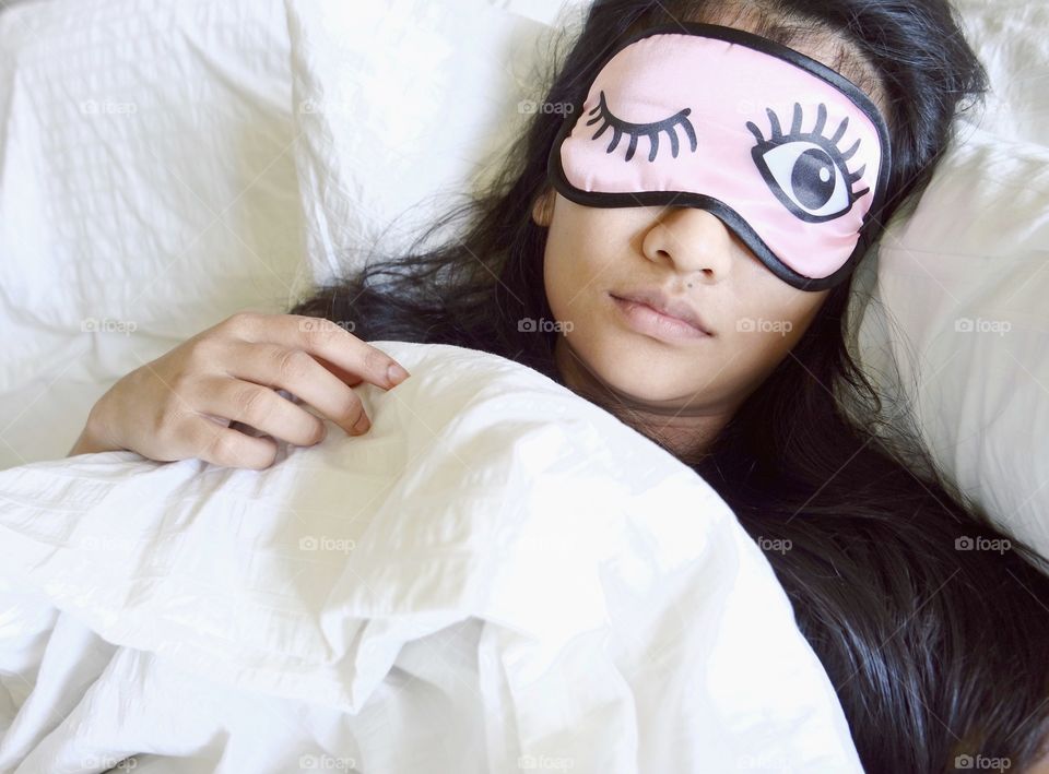 Girl lying on bed with sleep mask
