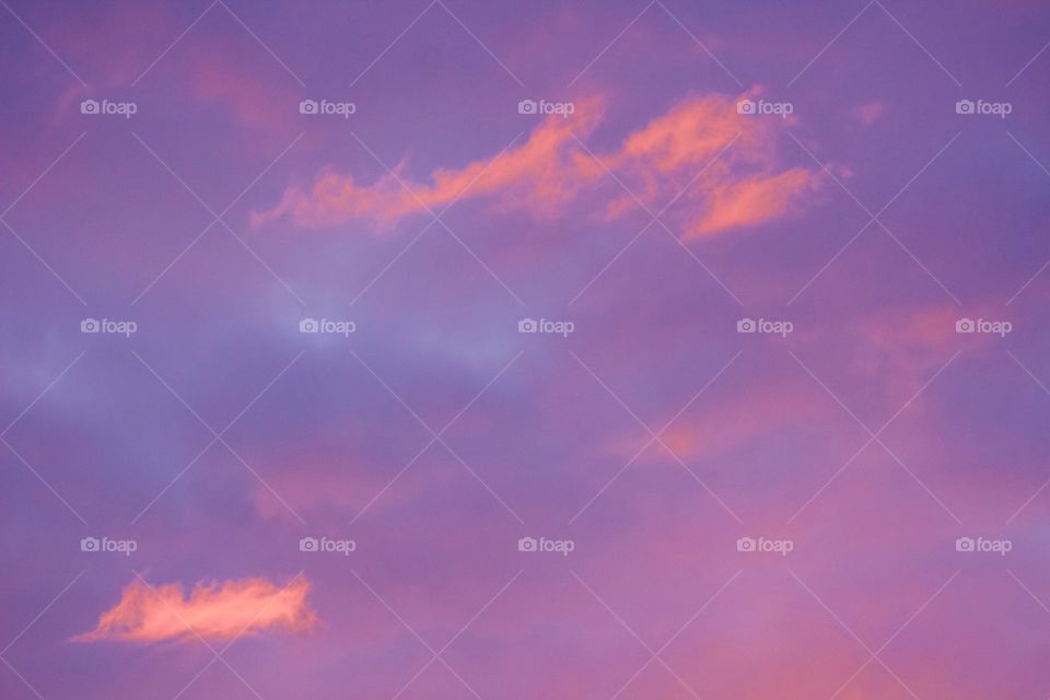 Purple and pink wispy clouds in a light blue sky 