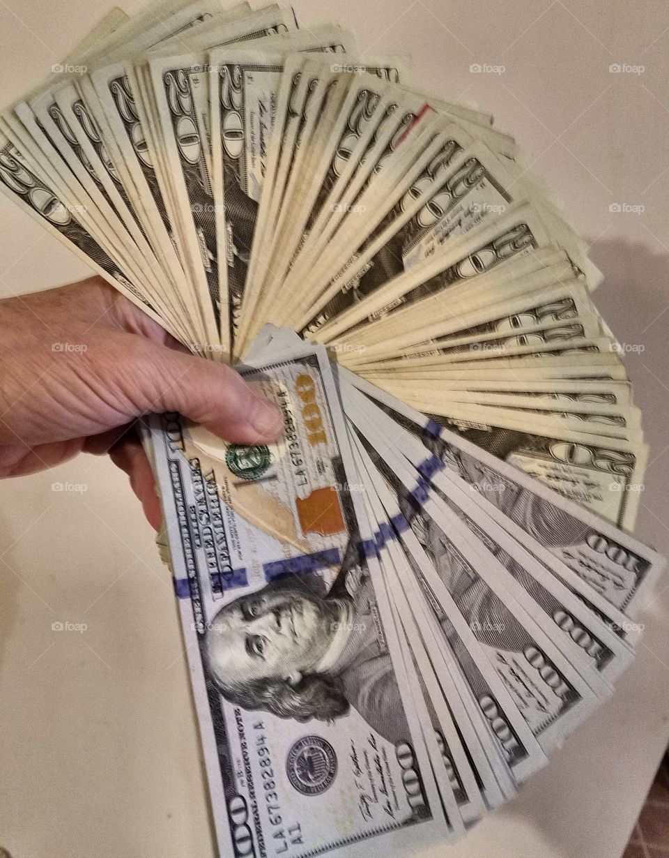 #clash of colour - hand holding a fan made of American paper money.