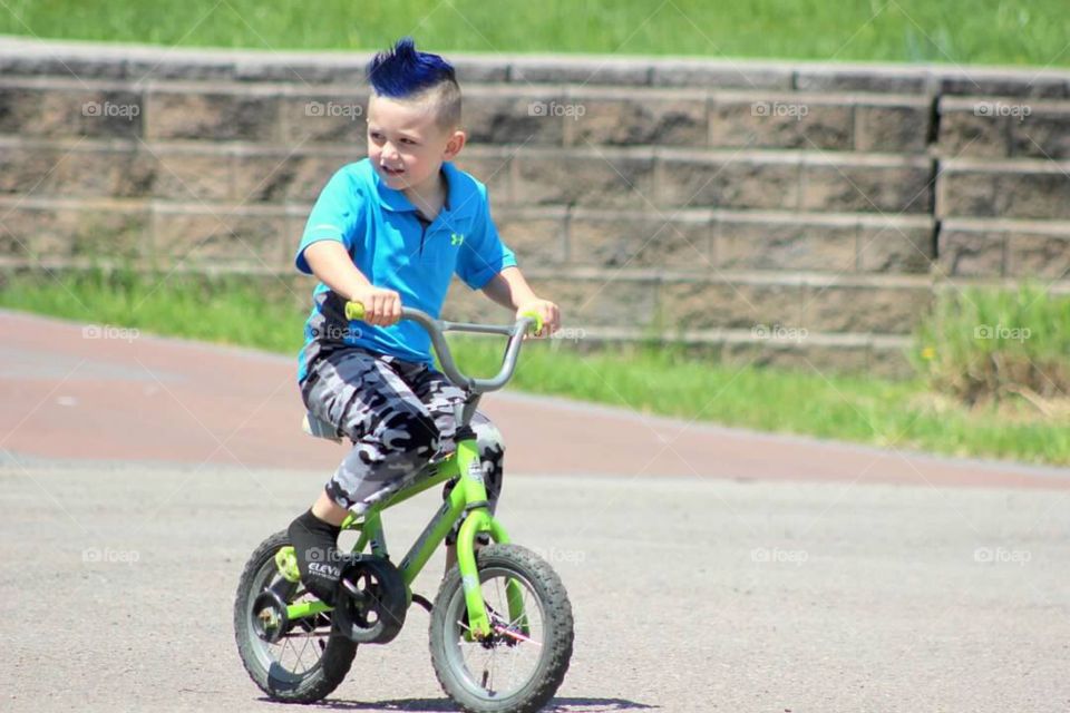 My blue haired little boy riding his bright green bike through our neighborhood. 