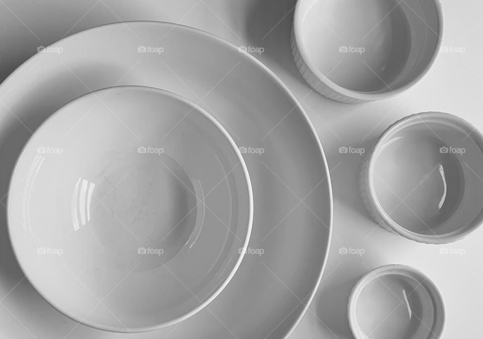 Assortment of white bowls and plates on a white table.