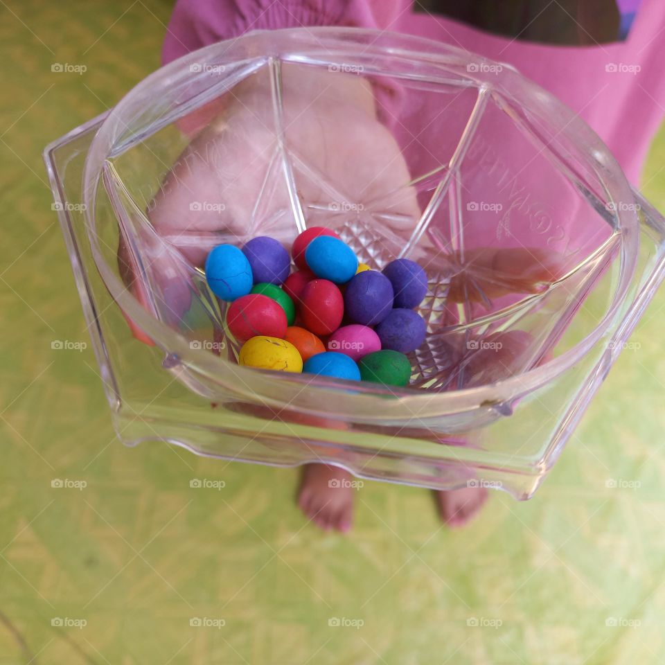 Colorful candies in plastic bowl on palm