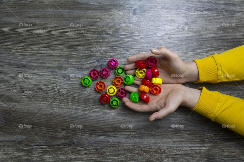 We collect garbage, plastic plugs and plastic to save our planet, nature and the environment. Men's hands lie on a gray wooden surface, which is used as a background or a surface with incident light.