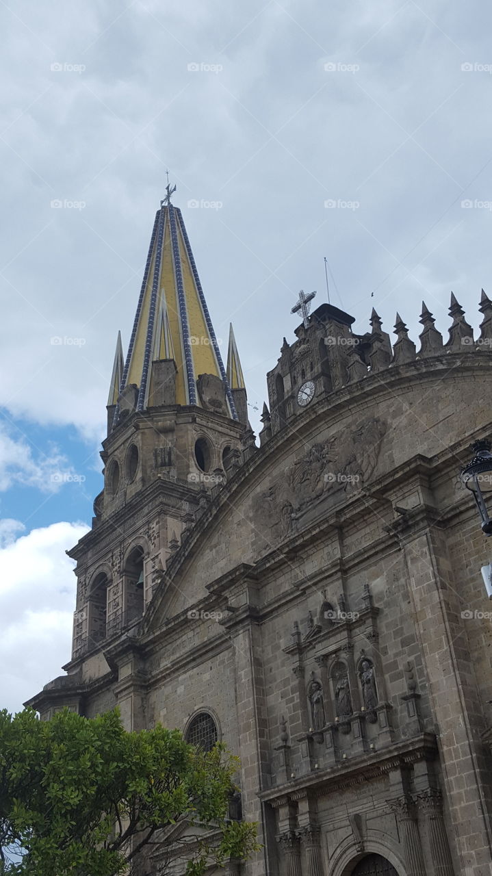 the Cathedral Basilica in Guadalajara on a cloudy day in the main square. The old architecture shows many arches and spires.