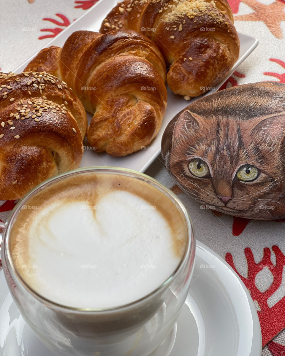 Artistic breakfast at the bar with a hand painted stone cat, croissants and cappuccino