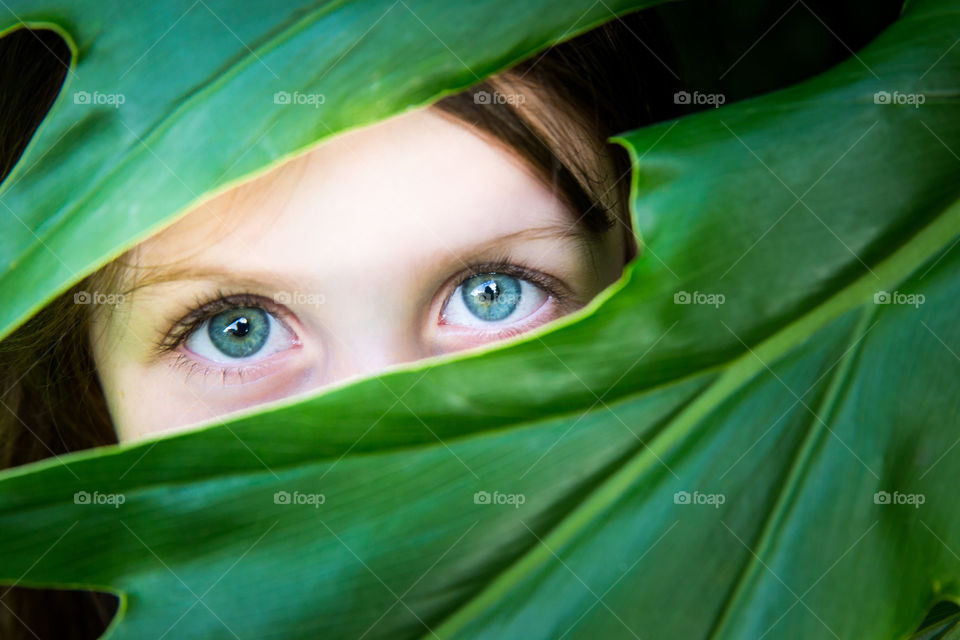 Green! Beautiful green eyes of a child framed by large green leaf
