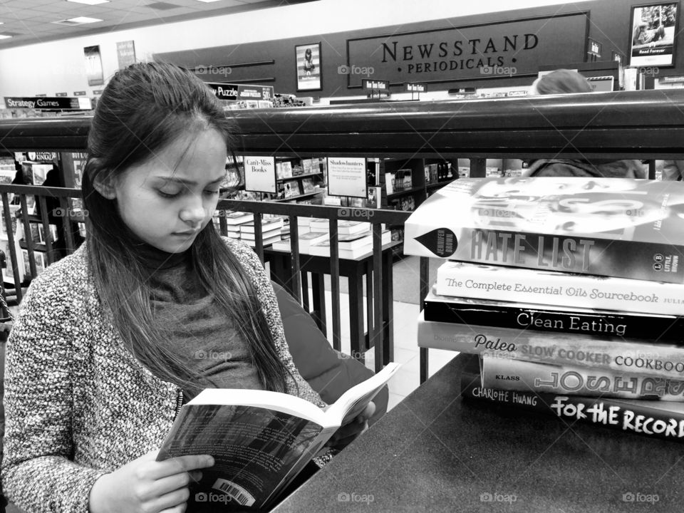 Teenage girl reading book in library