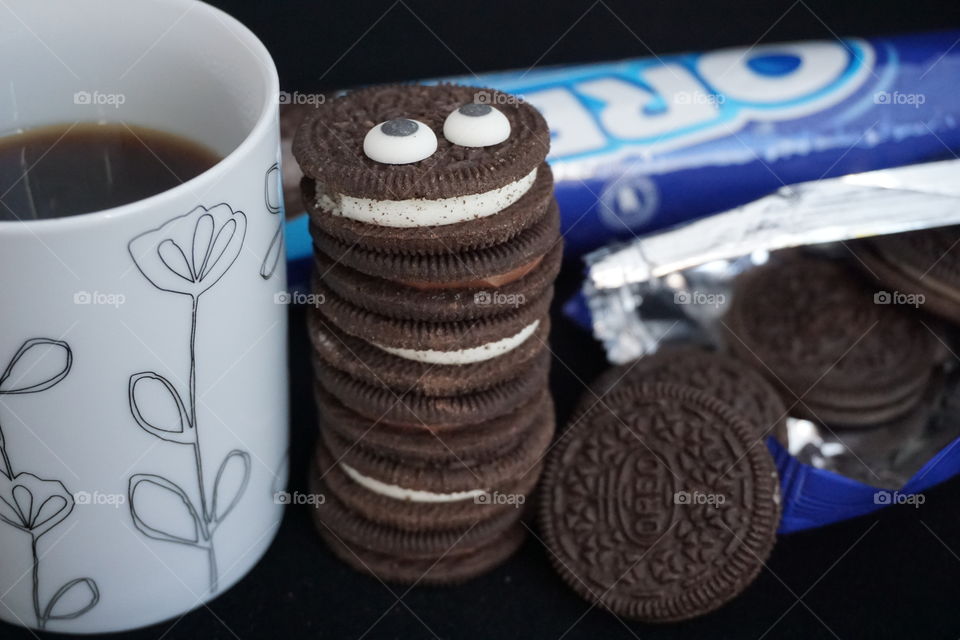 Tall Oreo Cookie Monster .. next to a mug of black coffee and a packet of Oreo biscuits 