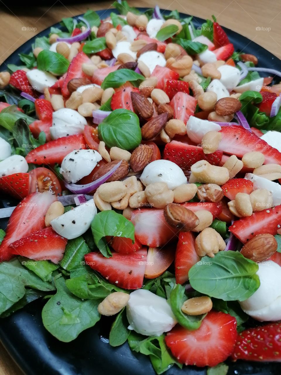 Homemade really delicious summer salad with strawberries, mozzarella, basil, arugula, nuts, red onion and black pepper. Is good! I recommend!