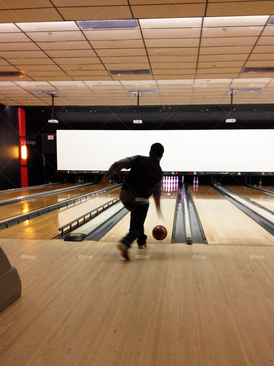 Silhouette of a man from behind playing bowling 