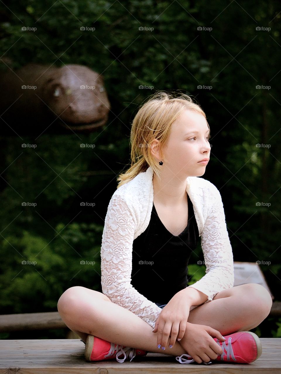 Sitting here. A girl sitting in the park with a dino in the background