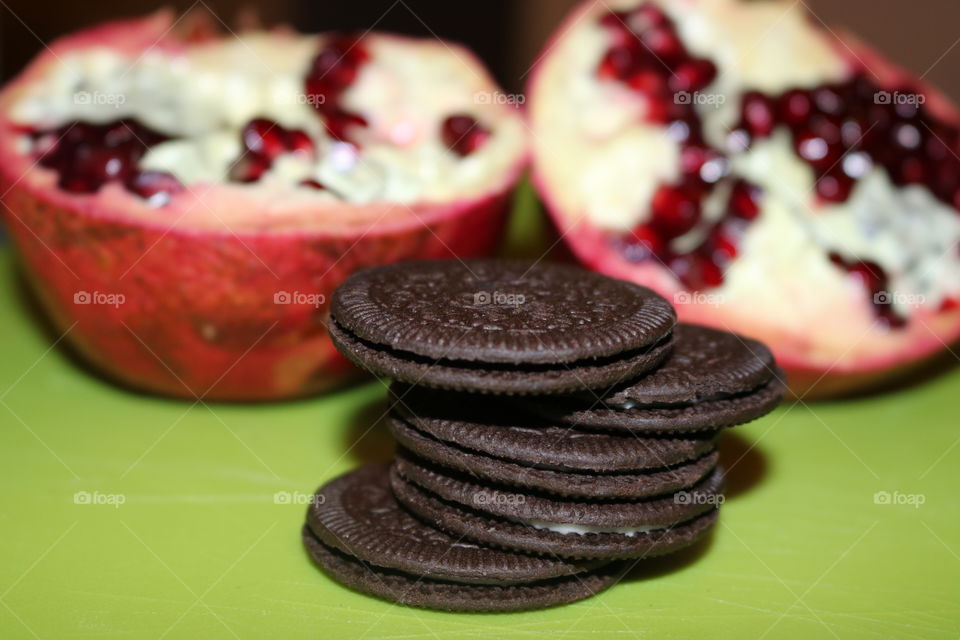 A stack of Oreo thins with freshly halved pomegranate in the background
