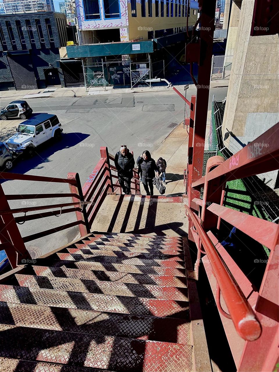This is the descending red metal staircase of the “Pulaski Bridge” at “Newtown Creek” in “Greenpoint”, Bklyn. Its “Bauhaus” inspired features come to life when the sun casts shadows that combine with its geometric shapes. 2024. Hypnotic Productions