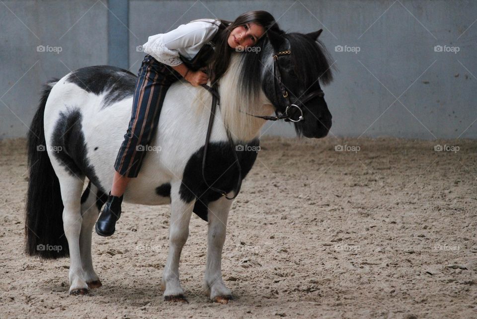 Teenage girl riding her horse in a stable