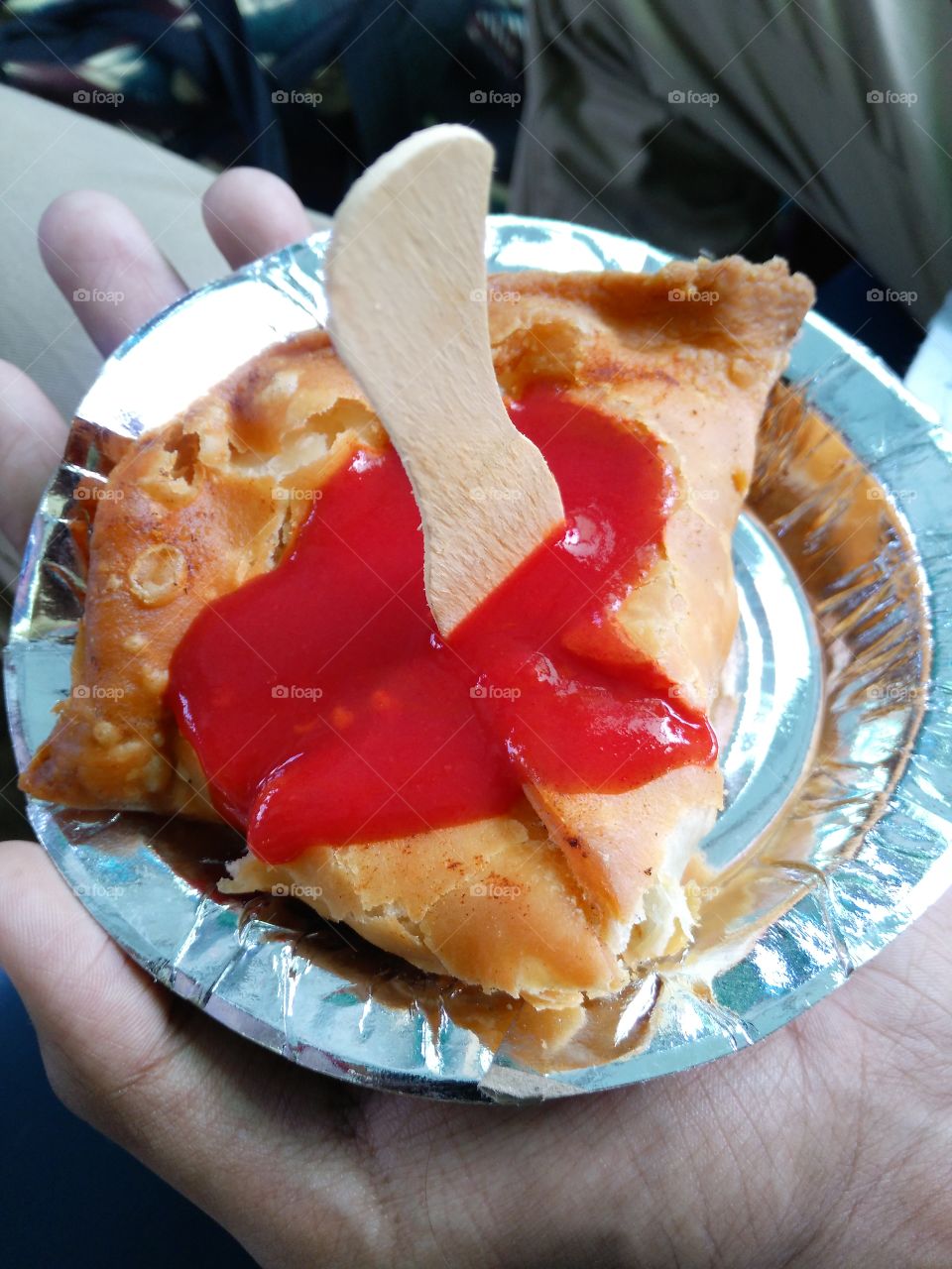 Human's hand holding fried samosa