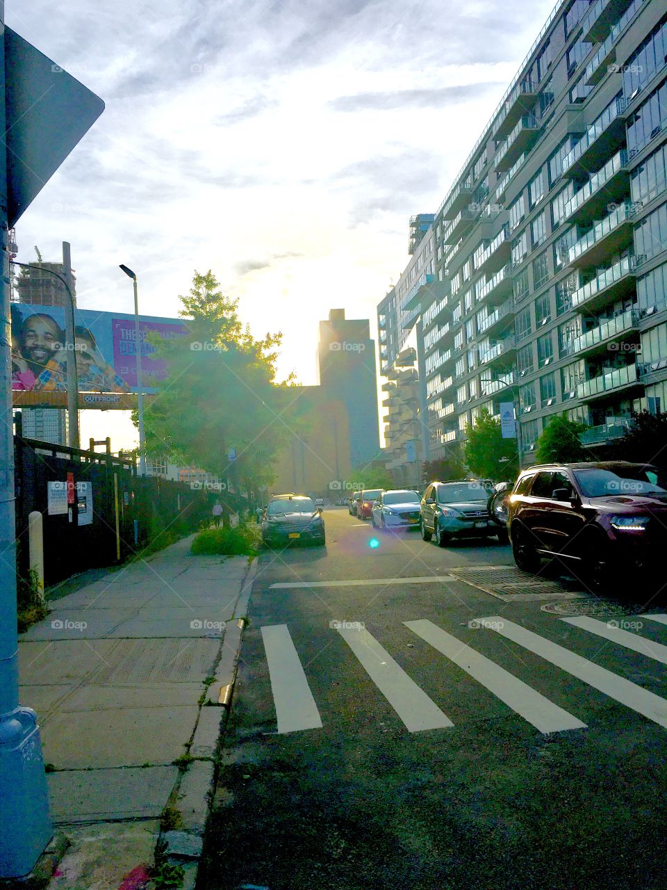 Borden Avenue along the waters of the East River at Newtown Creek, LIC, Queens at dusk. The faint sun is lighting up the sky in the distance and causes refractions and a lens flare. 2020. Hypnotic Productions