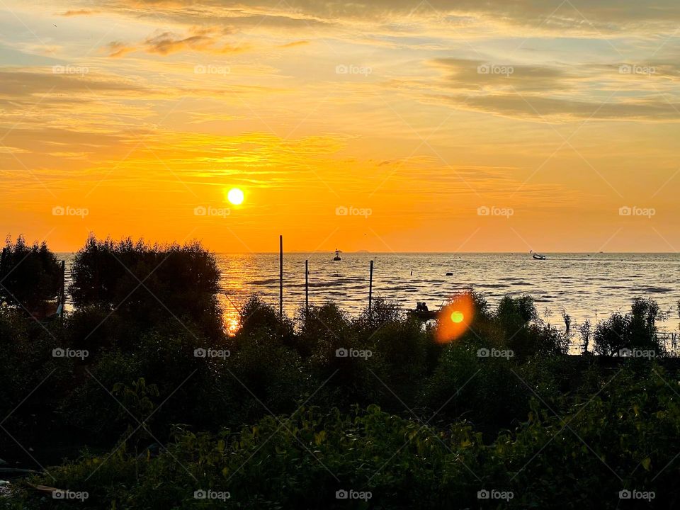 Sunset by the beach with orange sky and calm sea