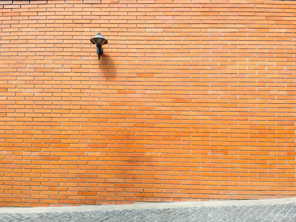 One lamp on the orange brick wall.