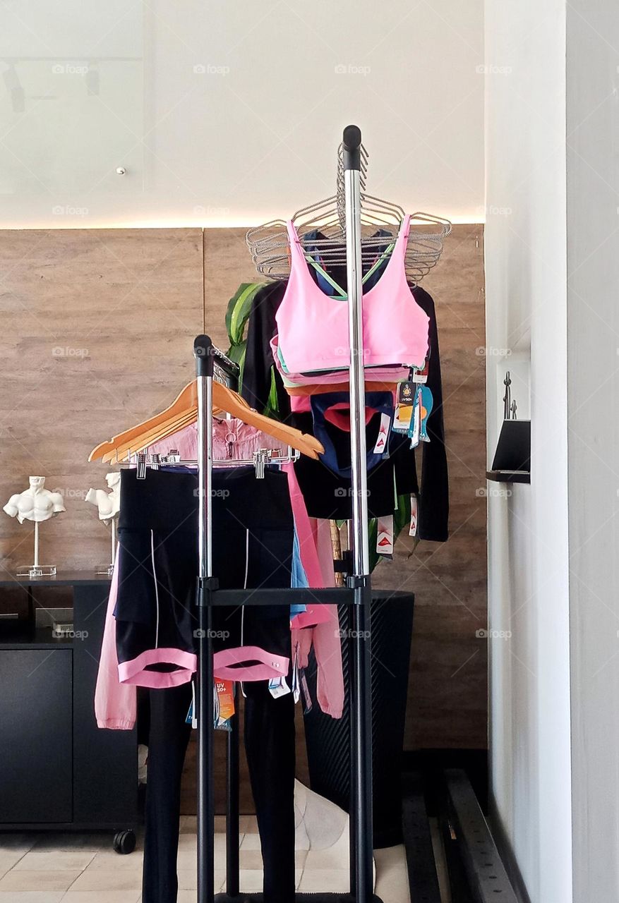 Two racks with fitness clothes for women. Pink top and shorts with pink details