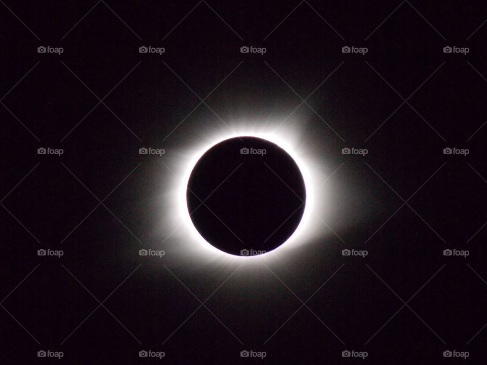 Solar eclipse in totality with bright stars and corona visible. 