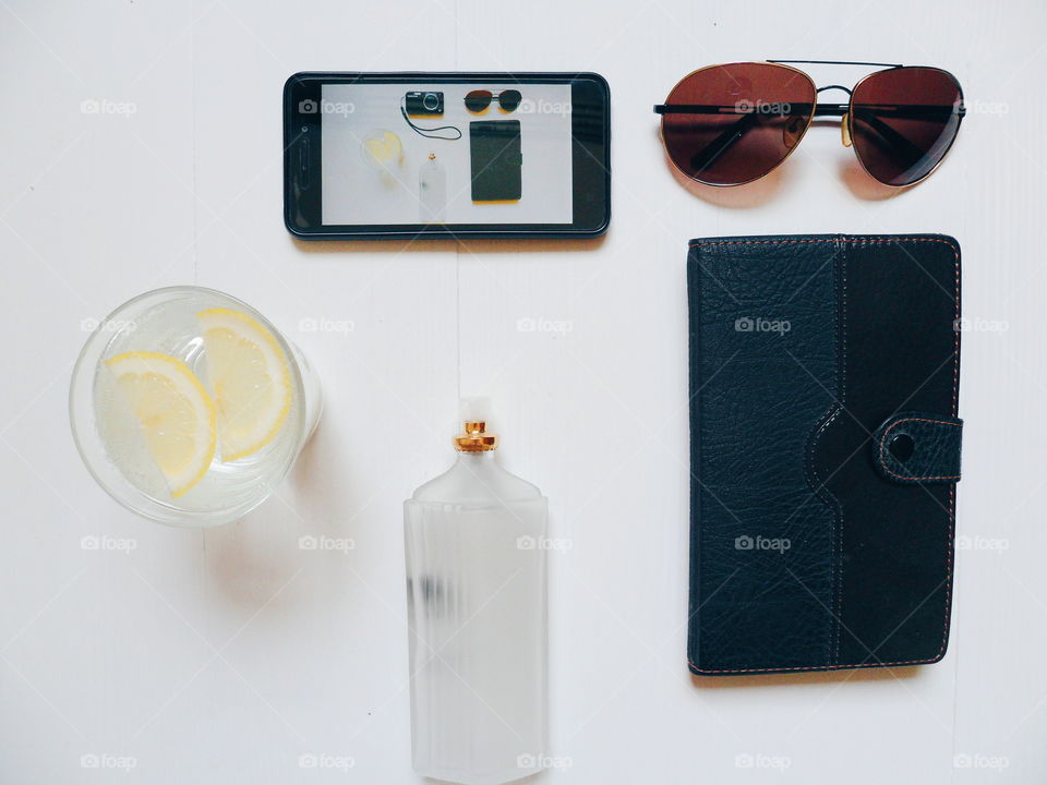 notebook, glasses, smartphone, eau de toilette and lemonade on a white background