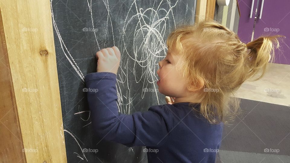 Little girl writing on blackboard