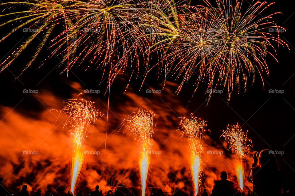 Colorful fireworks of various colors over night sky with spectators