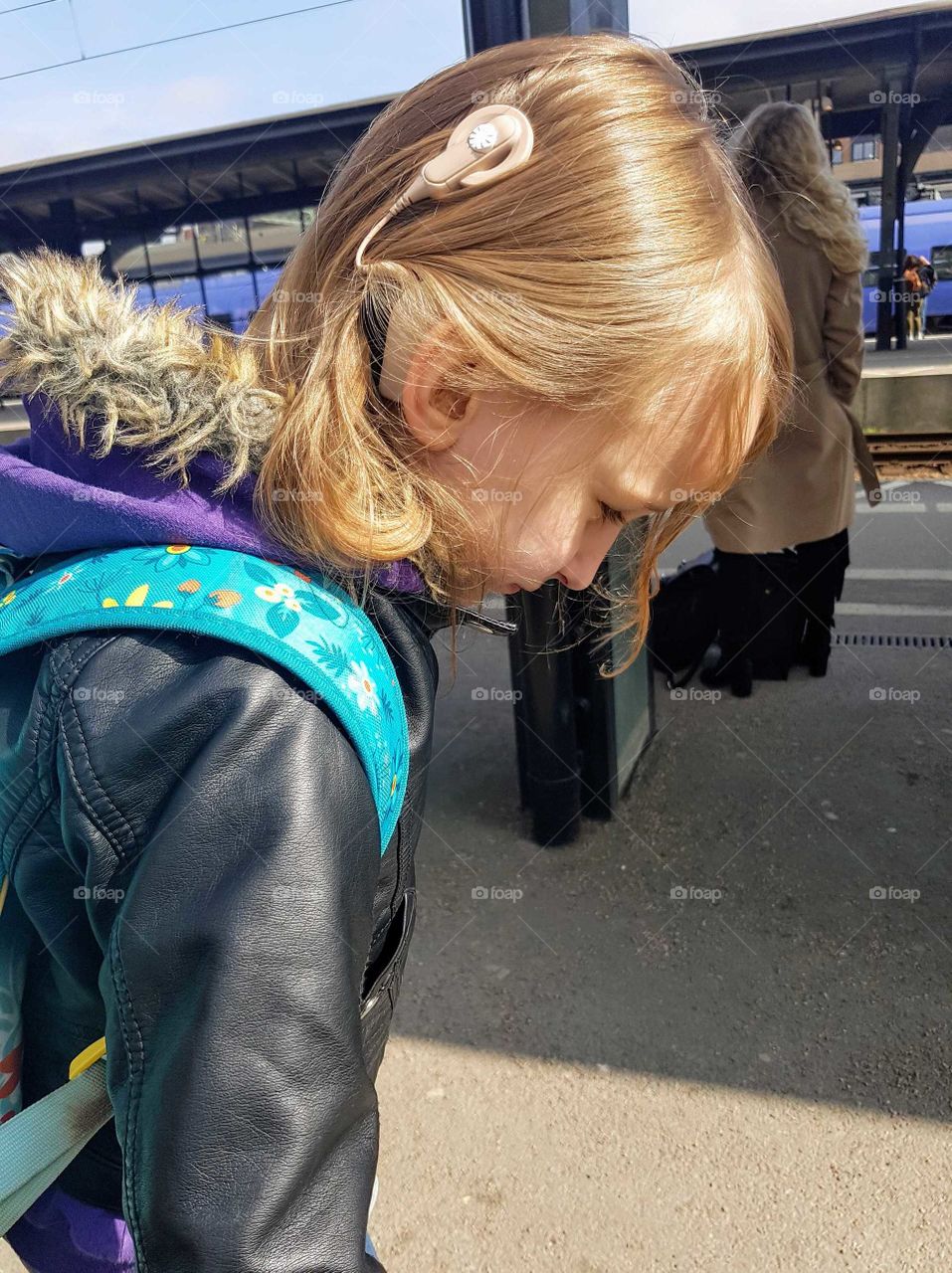 Girl with Cochlear implants waiting on the train