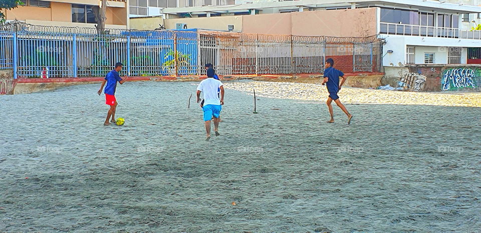 boys playing soccer on the beach