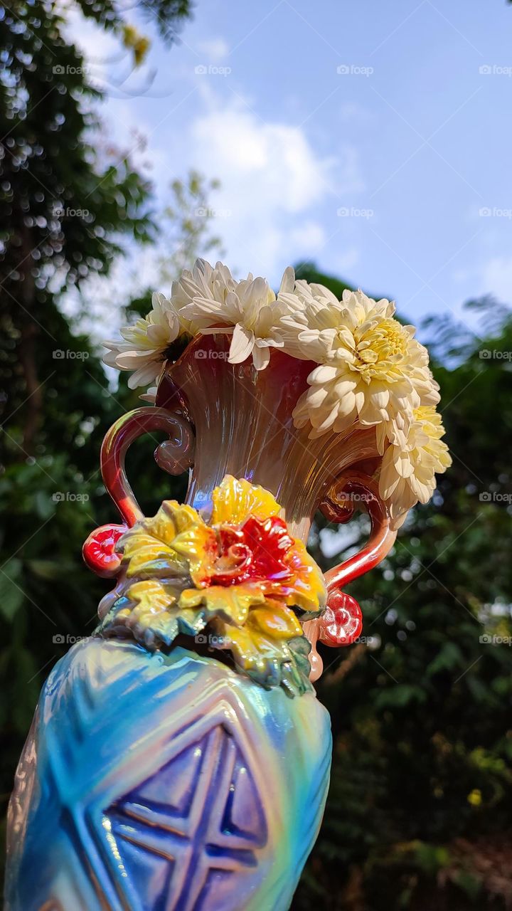 Beautiful white flowers in a colourful flowerpot with a flower sculpture