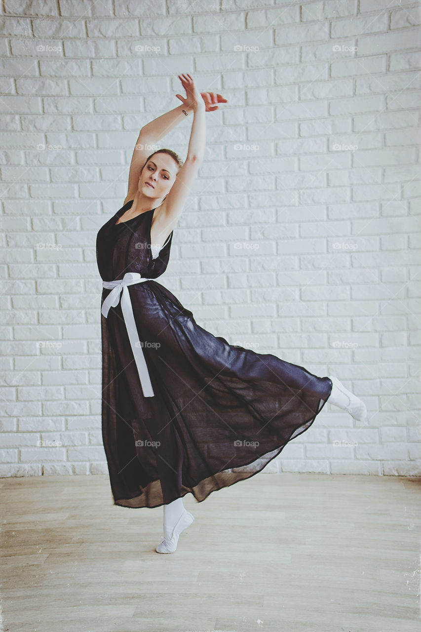 Young and graceful ballerina in pointe shoes and the tutu dances in the studio. Choreography and dancing classes concept. Creative ideas of ballet posing performance.