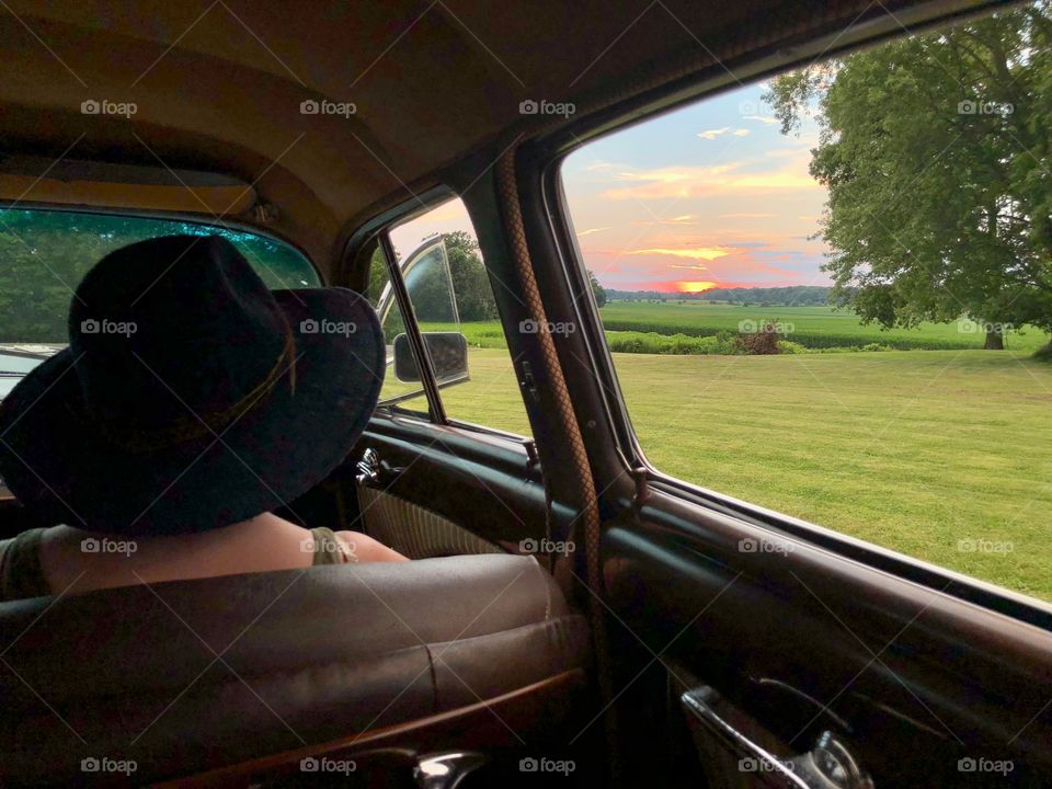 Girl in vintage car looking at the sunset