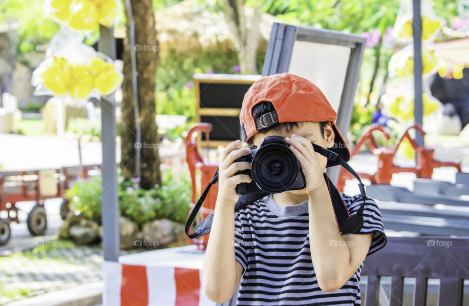 Hand boy holding the camera Taking pictures in park.