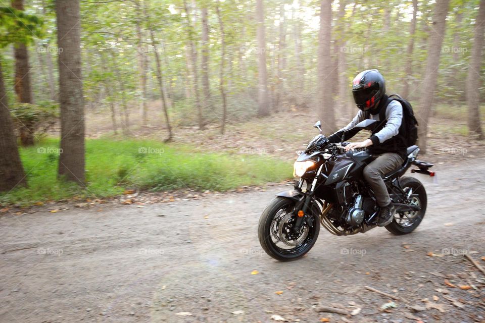 unrecognizable man seen riding a motorcycle in the woods