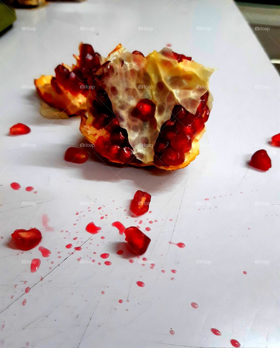 A close-up of a cracked pomegranate, with vibrant red seeds partially visible, showcasing the texture and contrast between the outer skin and the juicy interior. The cracked sections highlight the fruit's natural beauty and richness,a12mars 2024