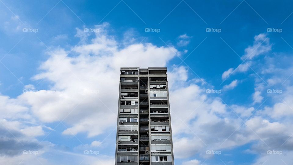 Old residential block against blue sky with white clouds