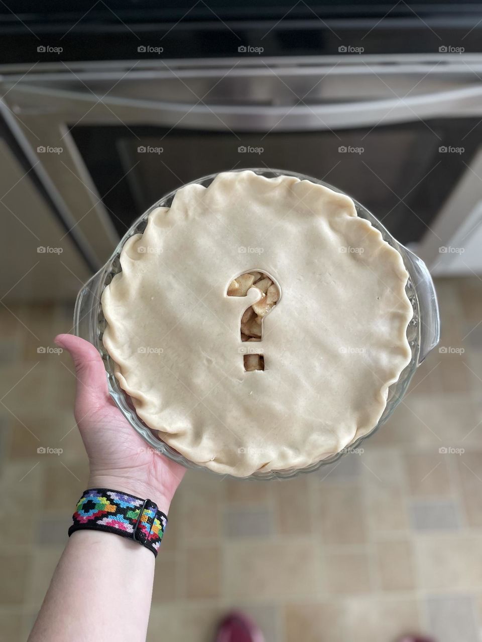 Putting the pie in the oven, making treats for your family, delicious apple pie, baking at home, baking pies, question mark on pie crust