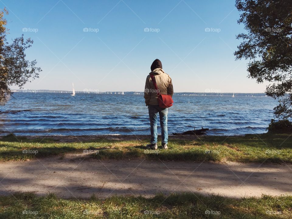 Teenager looking at lake. Teenager from behind looking at lake and boats in sunny autumn weather
