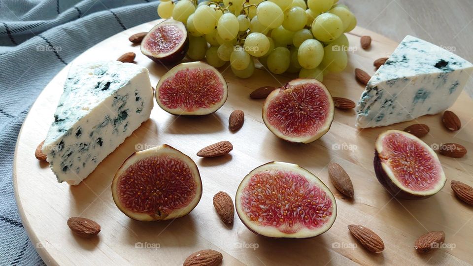 Health foods 🏃🤸‍♀️Blue cheese, almonds, grapes, figs on a wooden plate🍇🧀