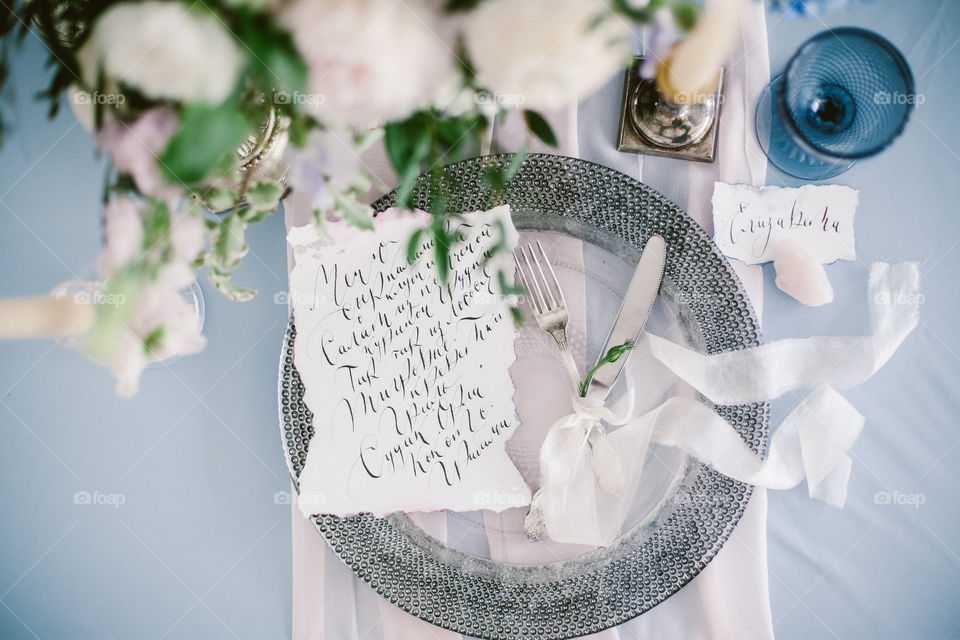 Graphic arts of beautiful wedding calligraphy cards and silver plate with cutlery on festive wedding table. 