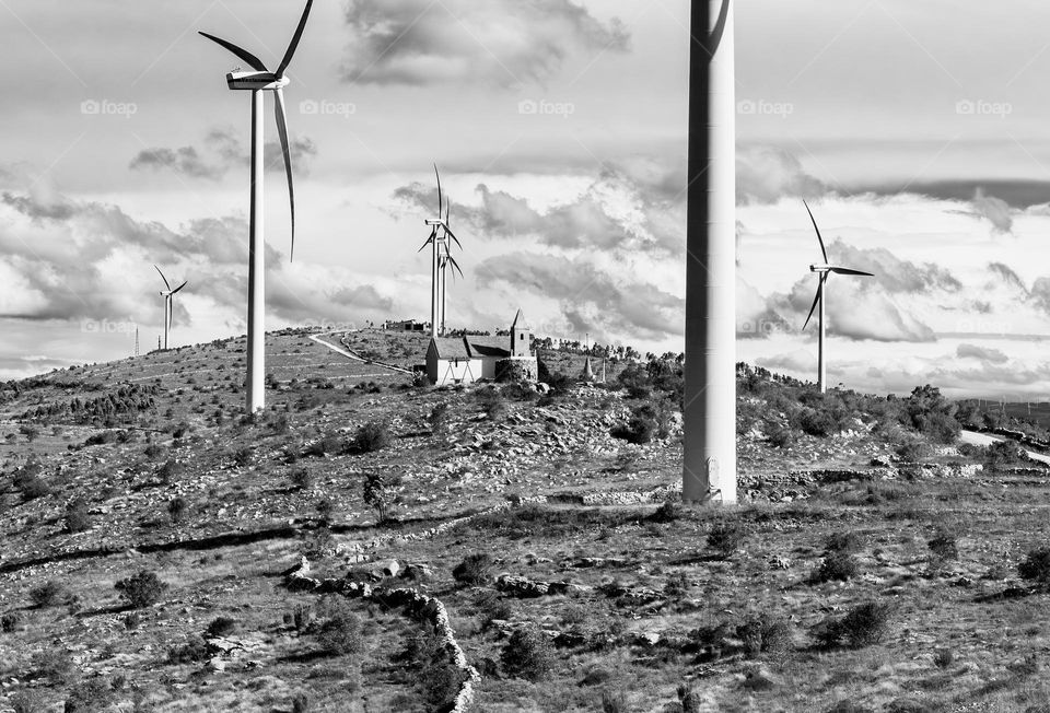 B&W landscape of a wind farm and hilltop chapel in Central Portugal