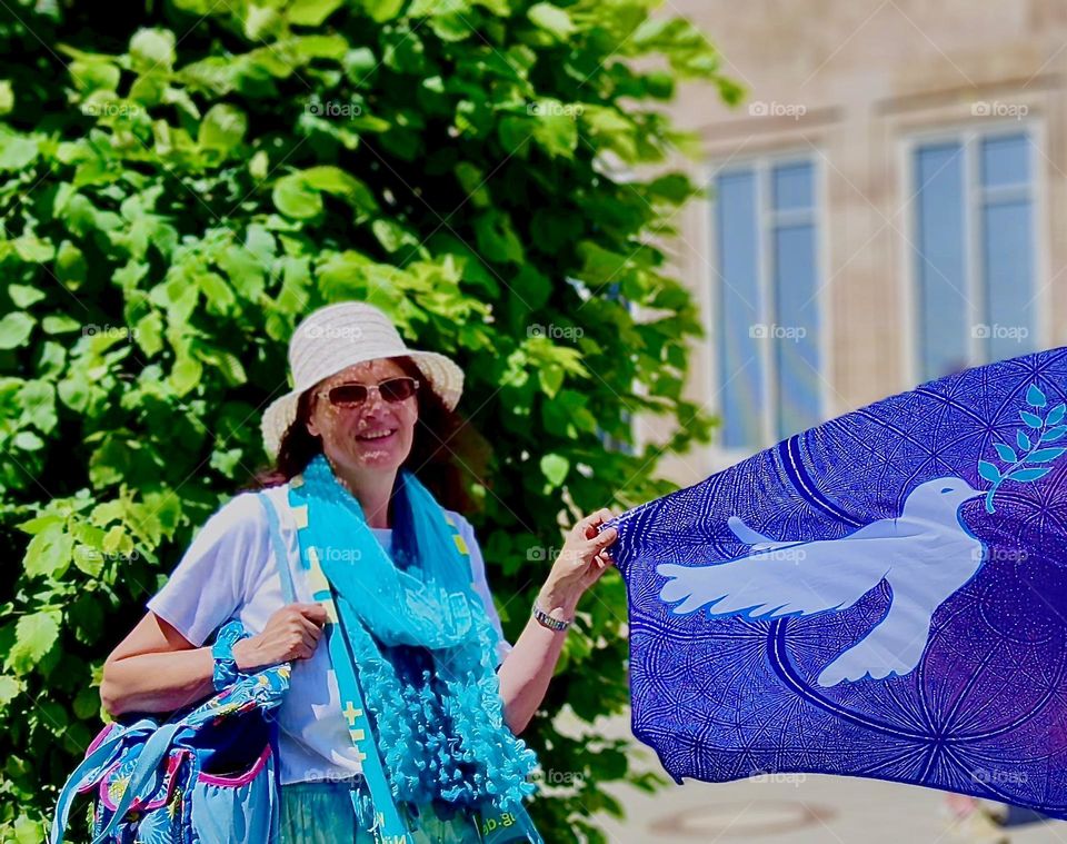 This lovely young lady is holding up the banner for the „Evangelical Church Day“ in „Nürnberg“, Germany: the image of a white dove on a violet background symbolizing the „Holy Spirit“ and divine inspiration. 2023. Hypnotic Productions