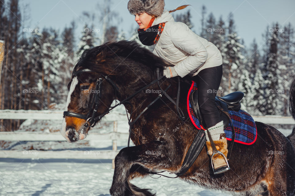 Teenage girl horseback jumping at cold winter day